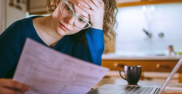 Een vrouw zuchtend met papieren in de hand