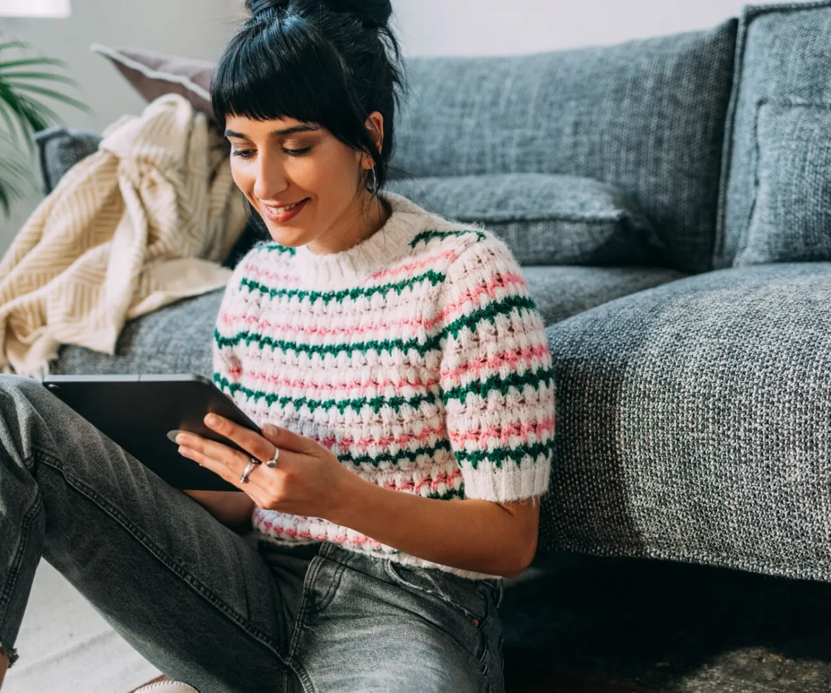 Meisje zit naast de zetel en kijkt naar haar iPad