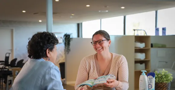 Vrouw geeft uitleg aan klant in de Goed zorgwinkel