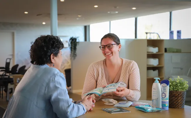 Vrouw geeft uitleg aan klant in de Goed zorgwinkel