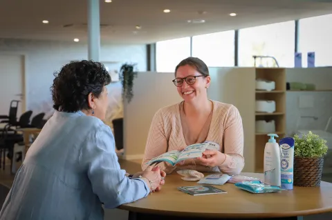 Vrouw geeft uitleg aan klant in de Goed zorgwinkel
