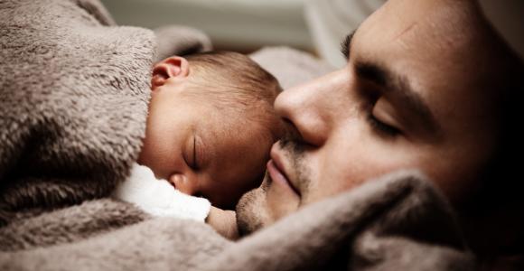 Kersverse baby in fleece deken slaapt op borstkas papa