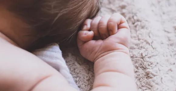 Baby ligt op rug, ingezoomd op hand en arm