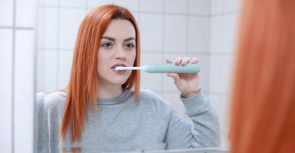 vrouw poetst met elektrische tandenborstel